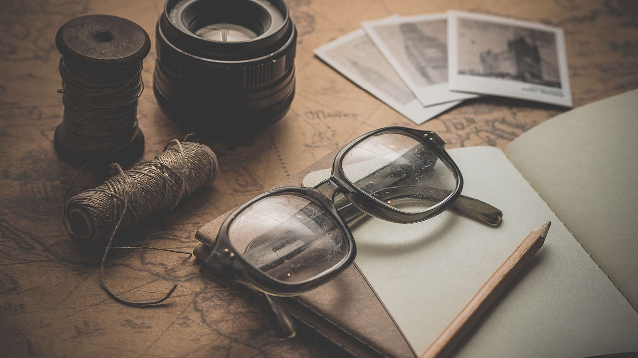 Glasses, a notebook, and camera lenses.