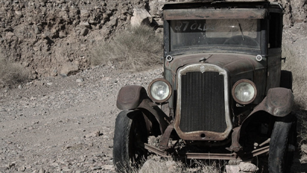 A vintage car abandoned in the desert.